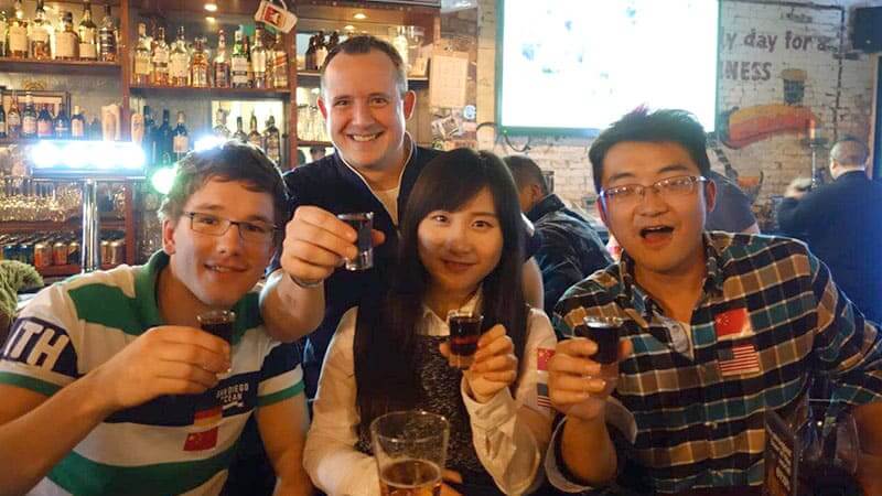 Students cheering with glasses of Baijiu at a baijiu tasting social event in Beijing