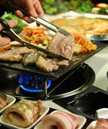 Up close photo of meat and vegetables on a Korean BBQ